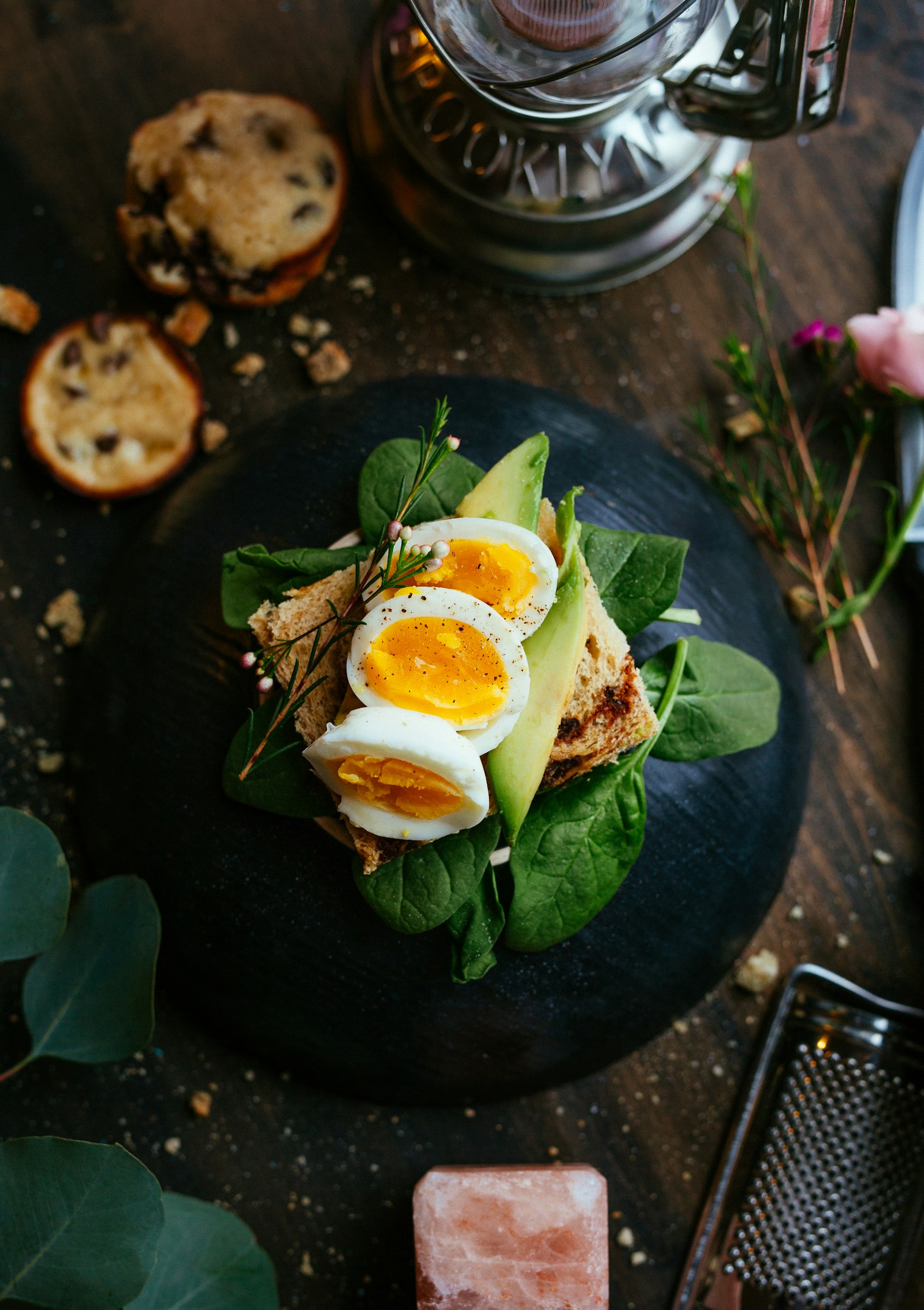 Open-faced toast with eggs, avocado, and greens on a plate — ordinary food, the mass that later leaves, mostly in the breath.